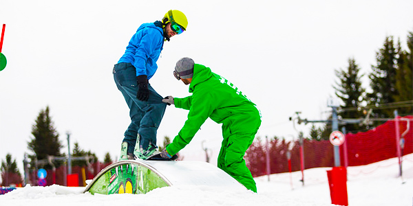 a snowboard and instructor practicing a trick
